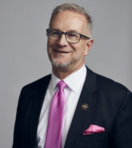 Dr. Benner of the AOA in black suit jacket with pink tie and pink pocket square. 