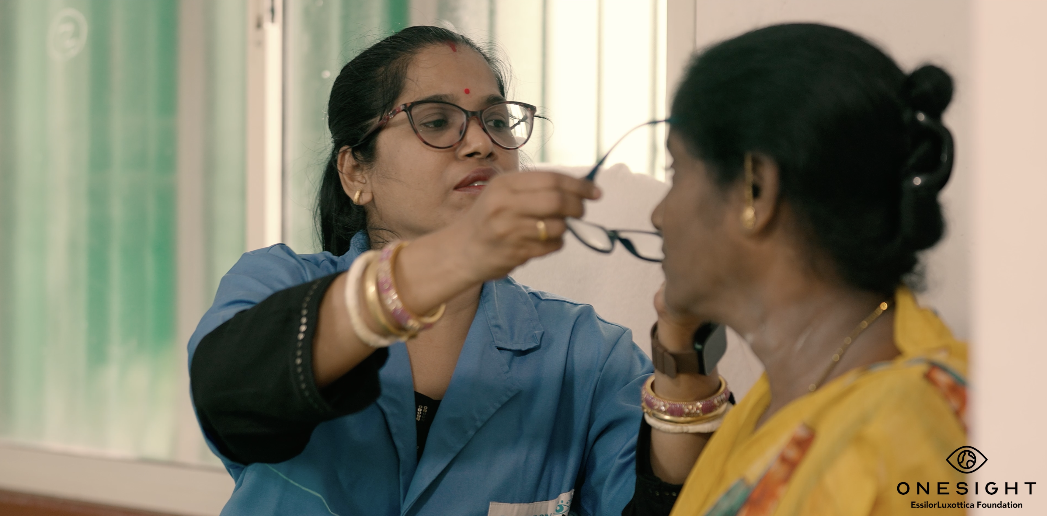 OneSight mission photo that shows eye care provider in India trying glasses on another woman