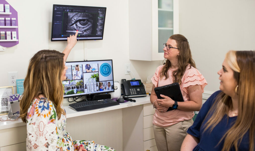 Dr. Denton pointing to an image of a patient's meibomian glands, teaching two staff members about dry eye